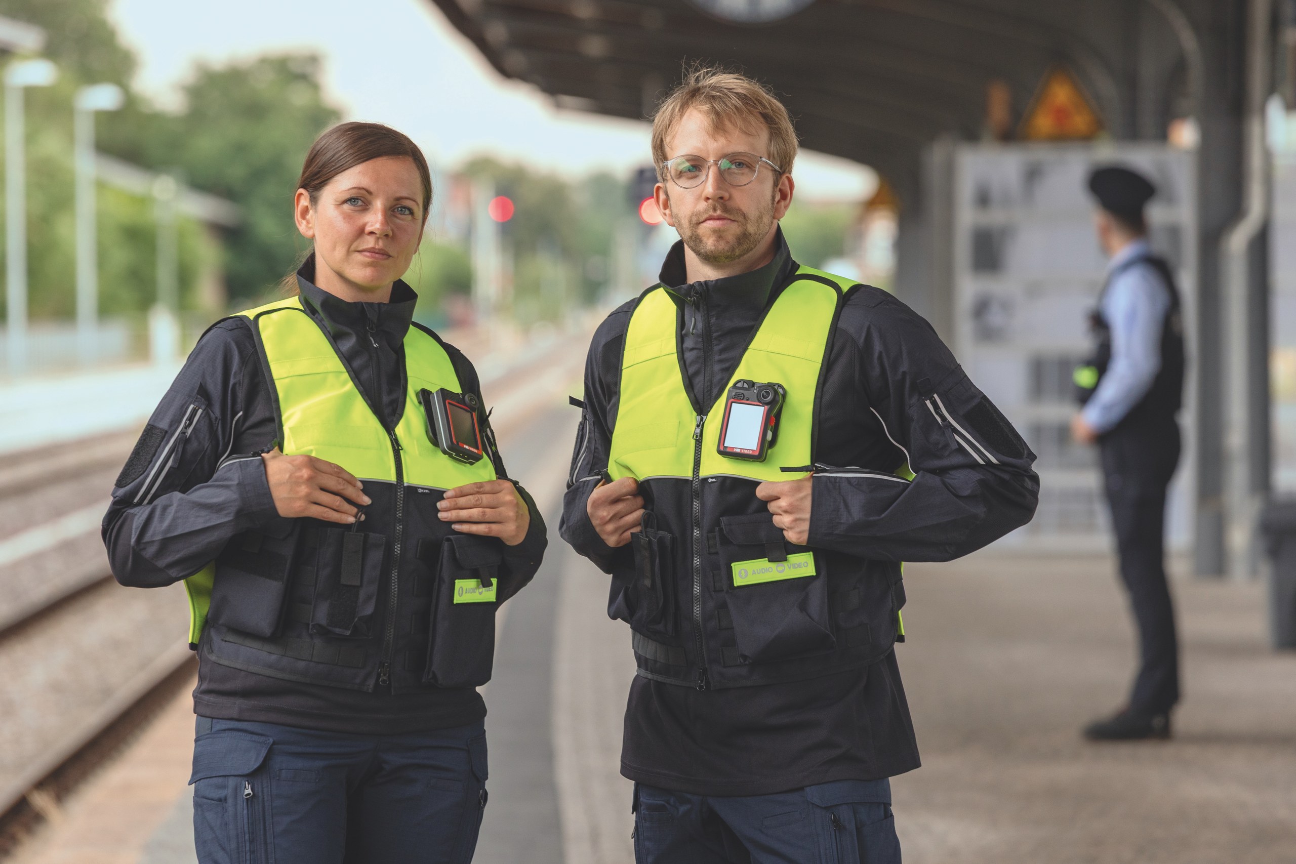 Zwei Sicherheitsdienst-Mitarbeiter auf dem Bahnsteig mit Warnwesten und Bodycams ausgerüstet